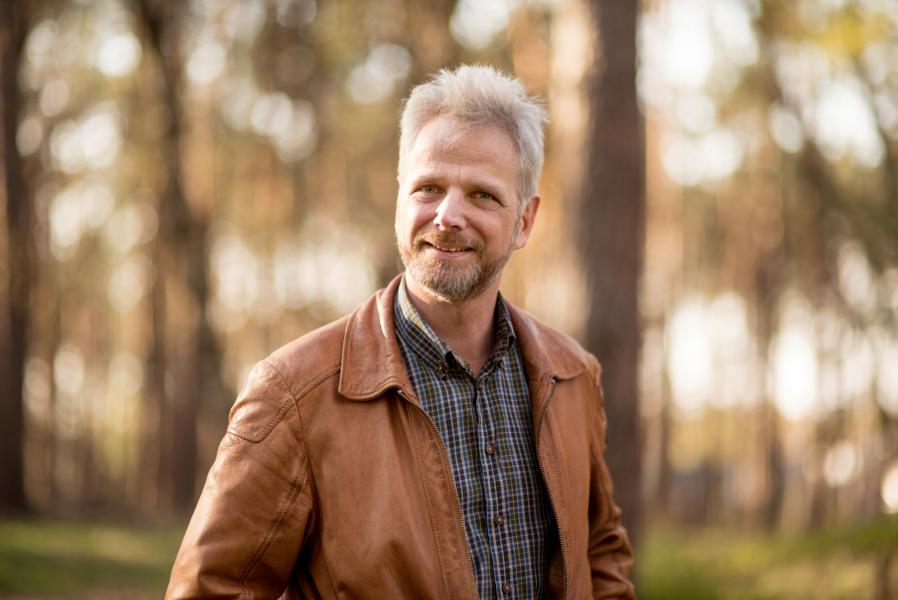 Mann im Wald mit Lederjacke.