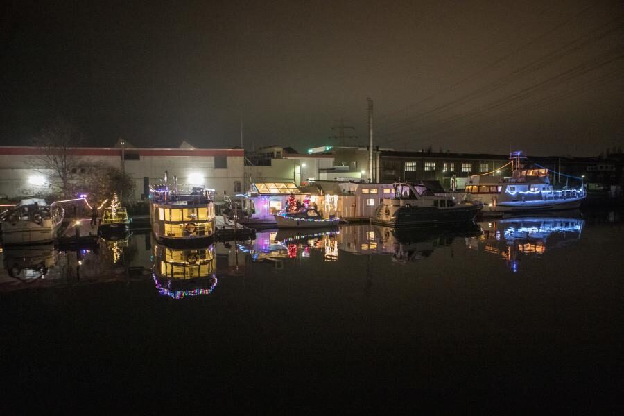 Weihnachtlich geschmückte Boote fahren durch den Harburger Binnenhafen