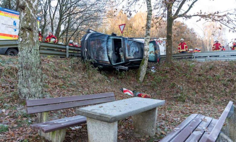 Das Foto zeigt eine kurvige Straße mit einem in der Böschung liegende, gegen einen Baum gedrücktem Auto.