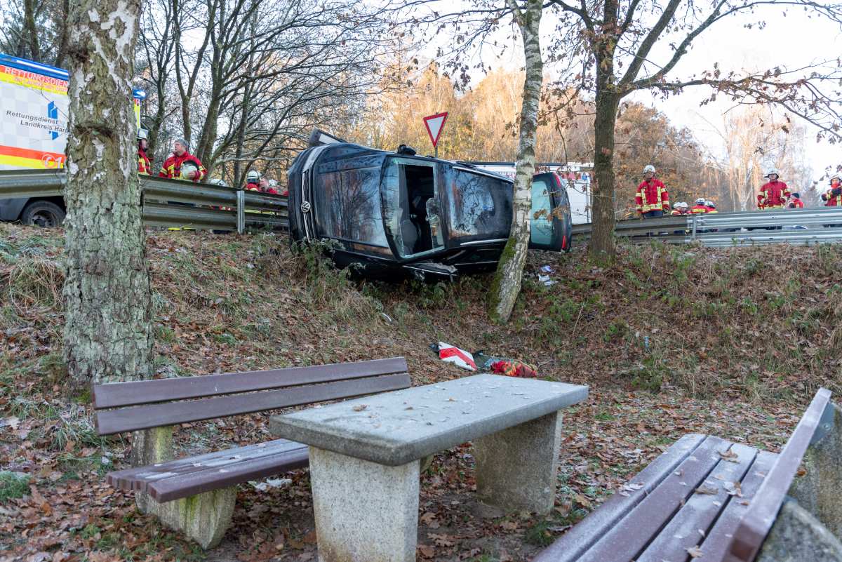 Das Foto zeigt eine kurvige Straße mit einem in der Böschung liegende, gegen einen Baum gedrücktem Auto.