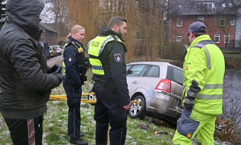 Das Foto zeigt Polizisten bei der Sicherstellung eines im Uferbereich liegenden Fahrzeugs