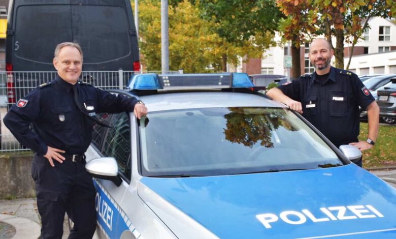 Zwei Polizisten posieren an einem Peterwagen.