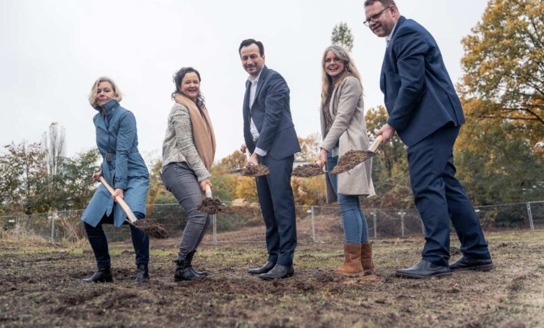 Die Akteure stehen mit Spaten in der Hand am Standort des geplanten Neubaus.