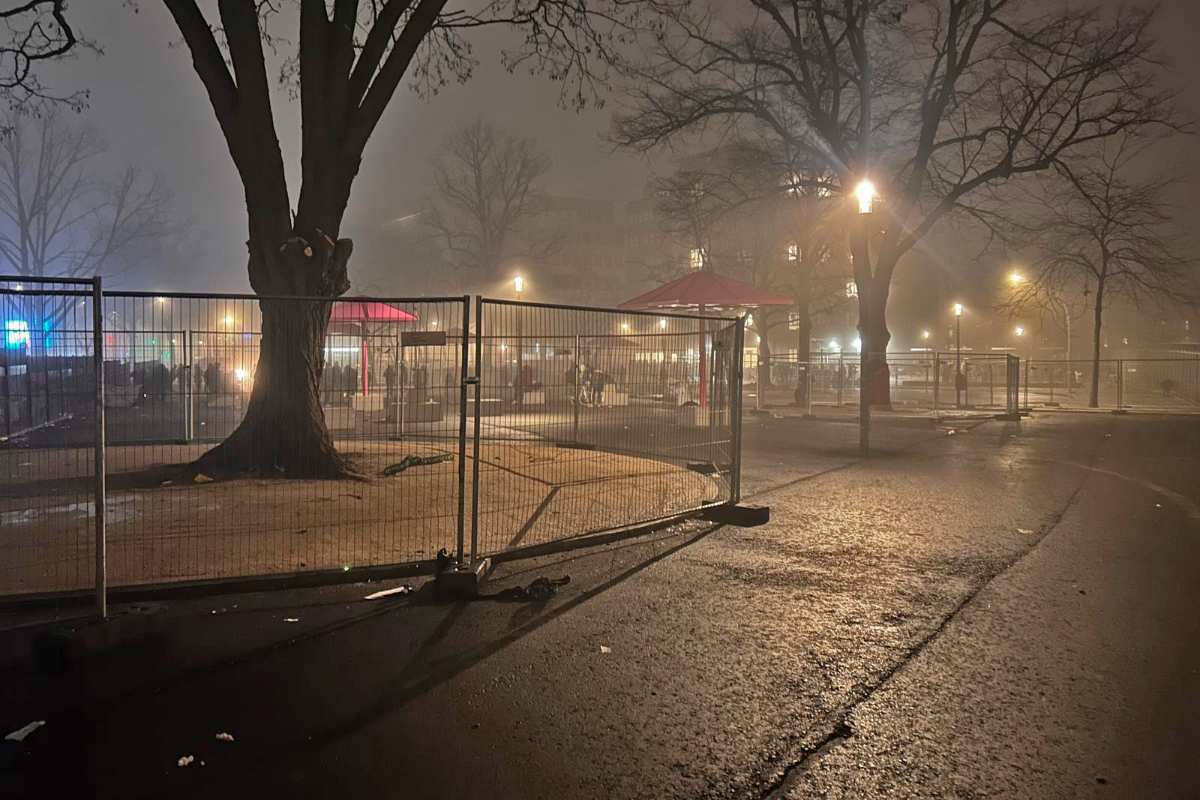 a fenced area with trees and people in the background