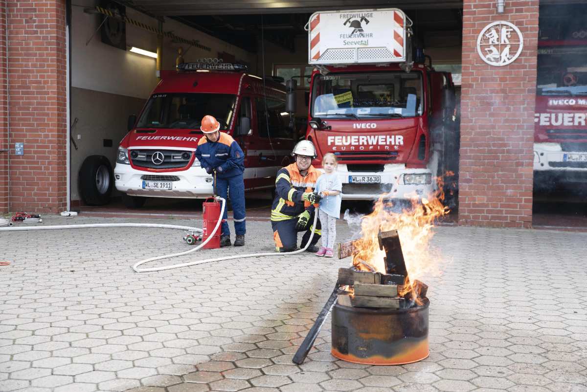 a group of firefighters and a child by a fire