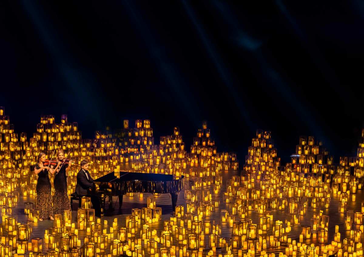 a group of people playing a piano and a piano in a room with candles