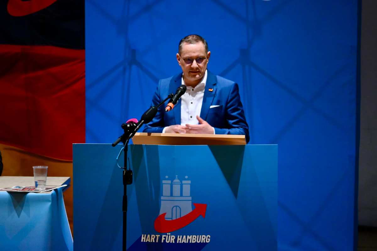 a man standing at a podium with microphones