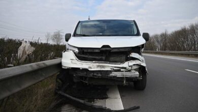 a white car with a damaged front end on the side of the road