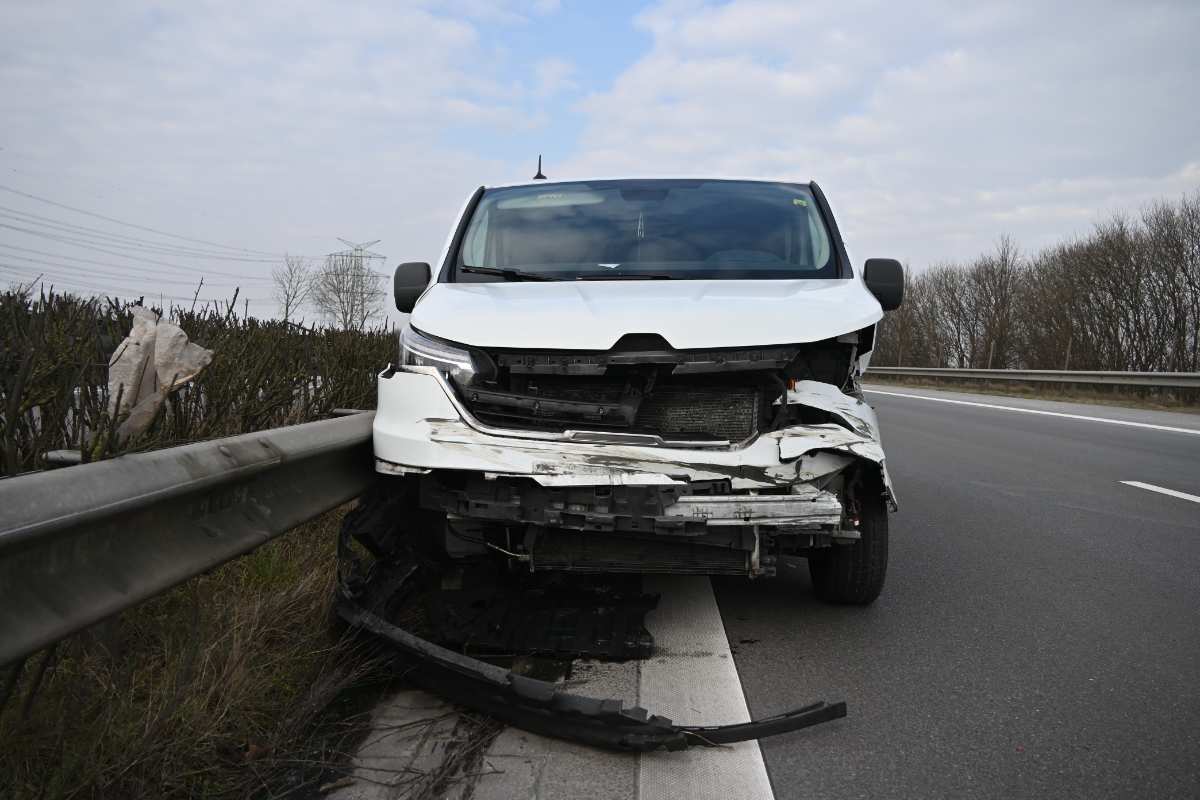 a white car with a damaged front end on the side of the road