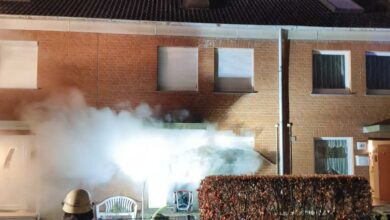 a firemen standing next to a building with a fire extinguisher