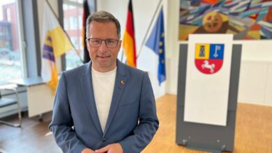 a man in a suit standing in front of flags