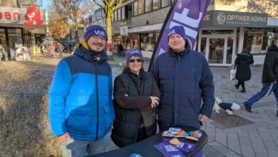 a group of people standing in front of a table with a purple banner