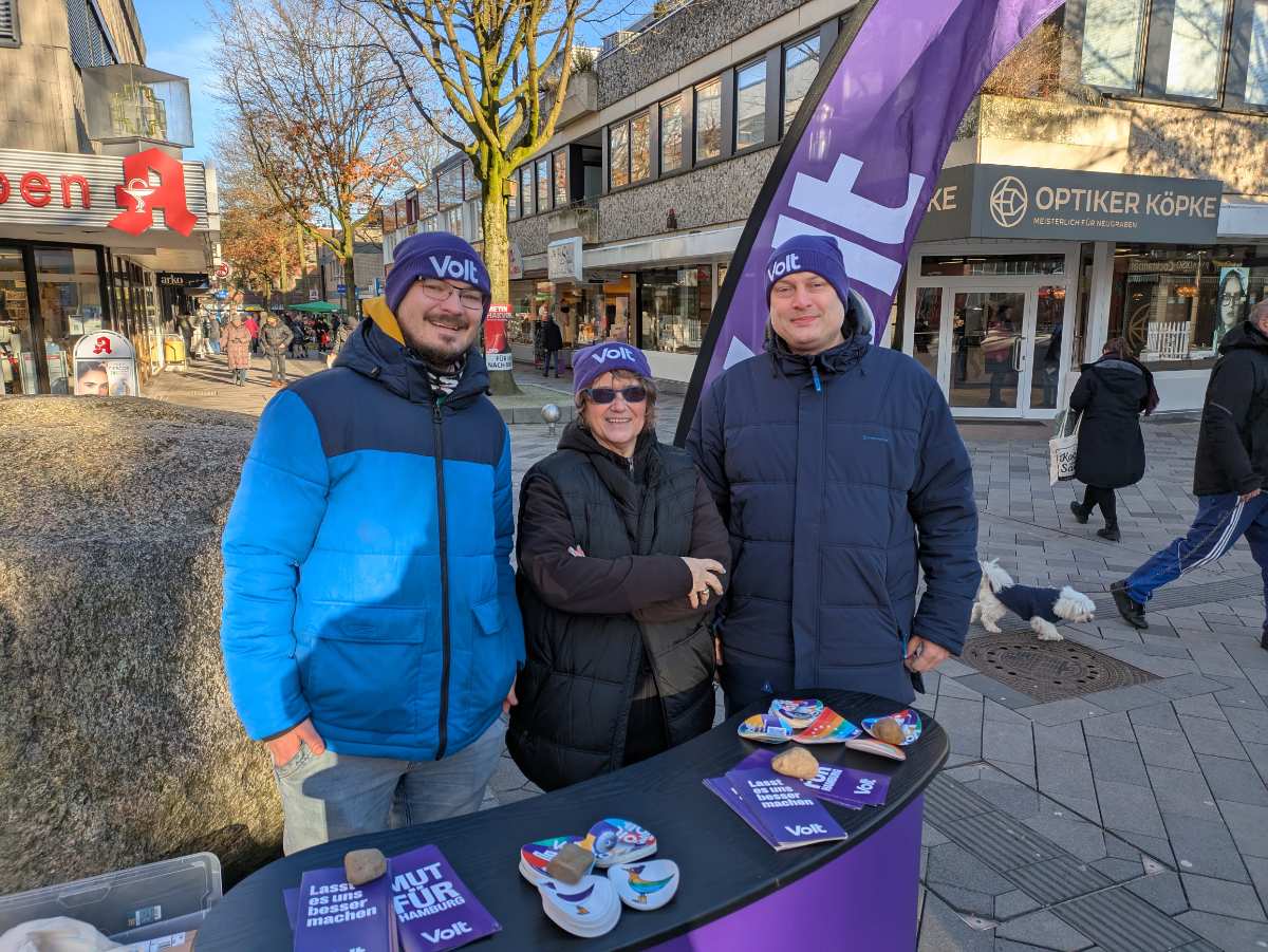 a group of people standing in front of a table with a purple banner