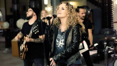 a woman singing into a microphone with a group of people playing instruments