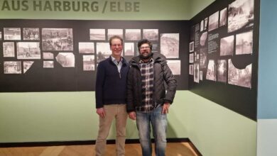 two men standing in a room with pictures on the wall