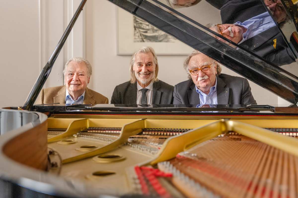 a group of men sitting at a piano