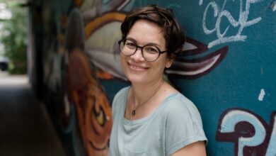 a woman smiling in front of a wall with graffiti