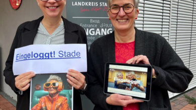 two women holding a tablet and a sign