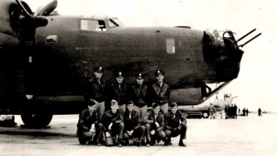 a group of men posing in front of a plane