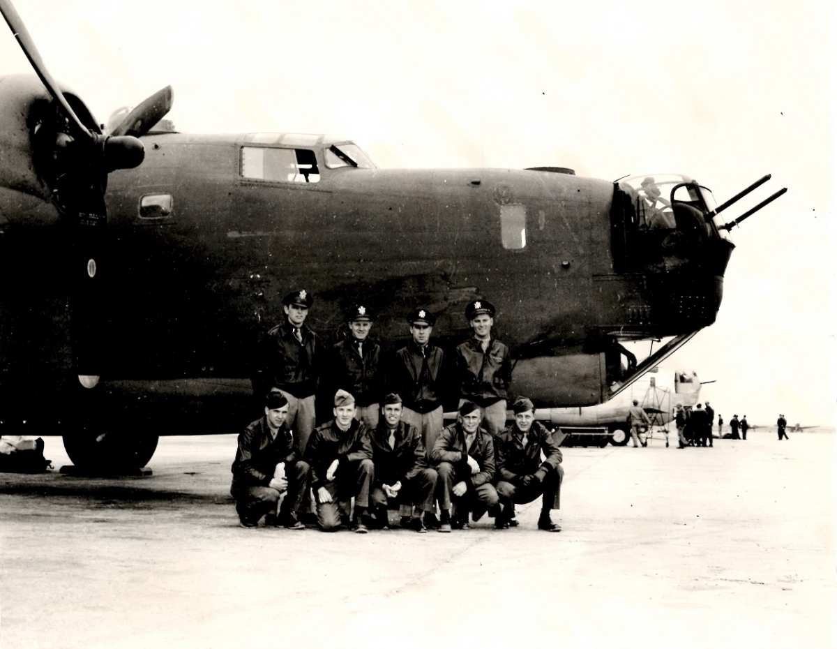 a group of men posing in front of a plane