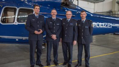 a group of men in uniform standing in front of a helicopter