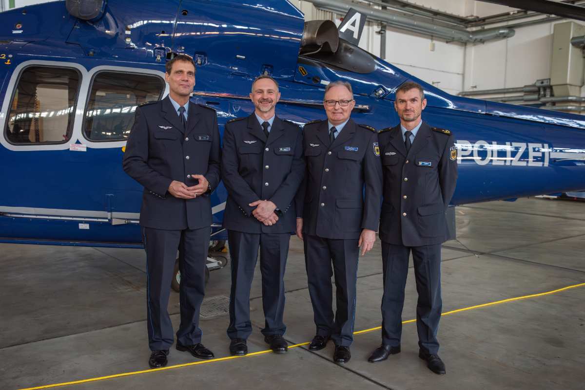 a group of men in uniform standing in front of a helicopter