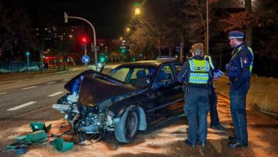 police officers standing around a wrecked car on a street