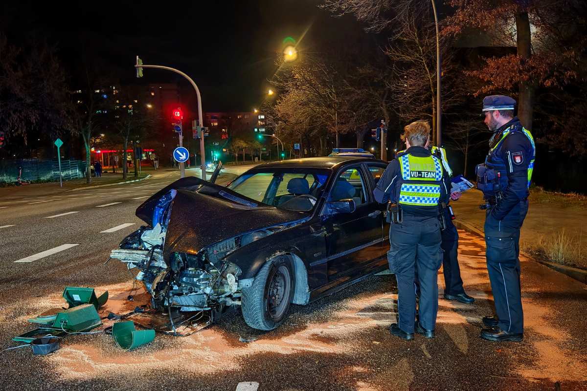 police officers standing around a wrecked car on a street