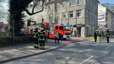 a group of firemen standing on a street near a fire truck