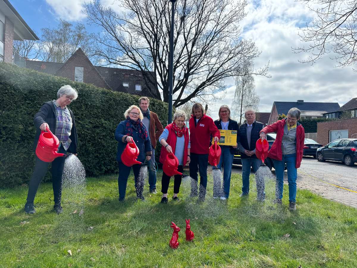 a group of people watering grass with red watering cans