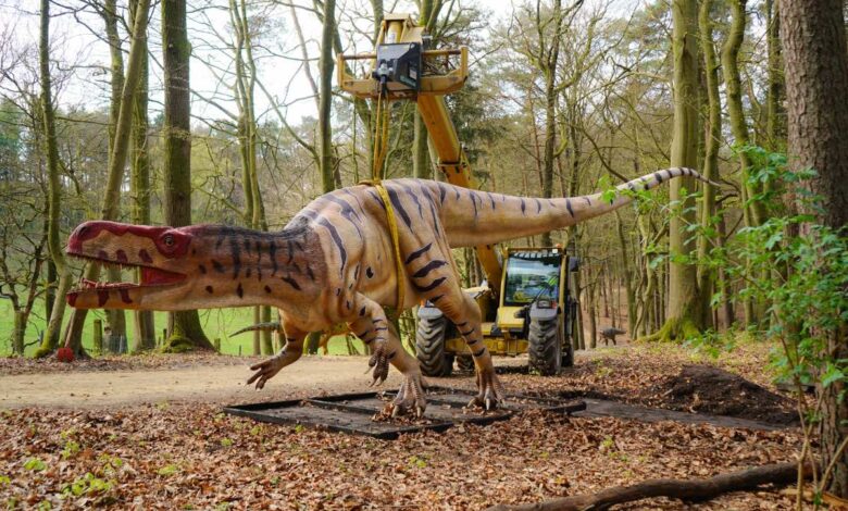 a dinosaur statue in the woods