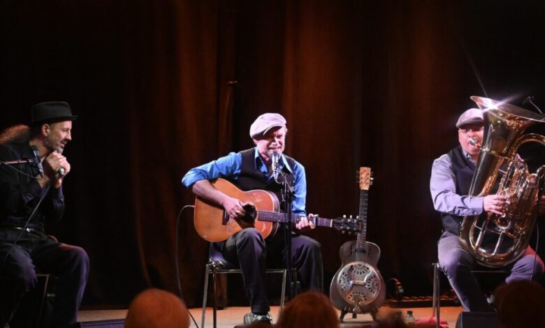 a group of men playing guitars on a stage