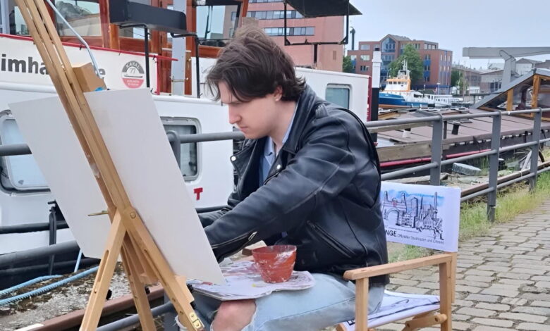 a man sitting on a chair painting on a canvas