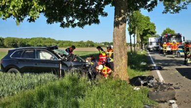 a group of people around a car that has been crashed on the side of the road
