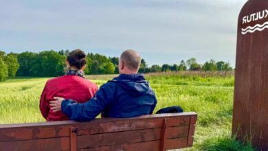 a man and woman sitting on a bench in a field