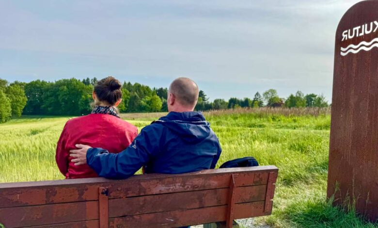 a man and woman sitting on a bench in a field