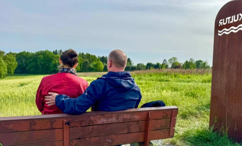 a man and woman sitting on a bench in a field