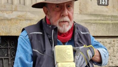a man wearing a cowboy hat and gloves holding a stack of gold blocks