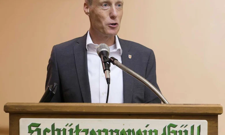 a man standing at a podium with microphones