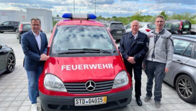 a group of men standing next to a red car