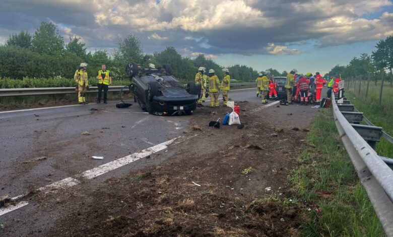a car crashed into a road with firemen and a group of people