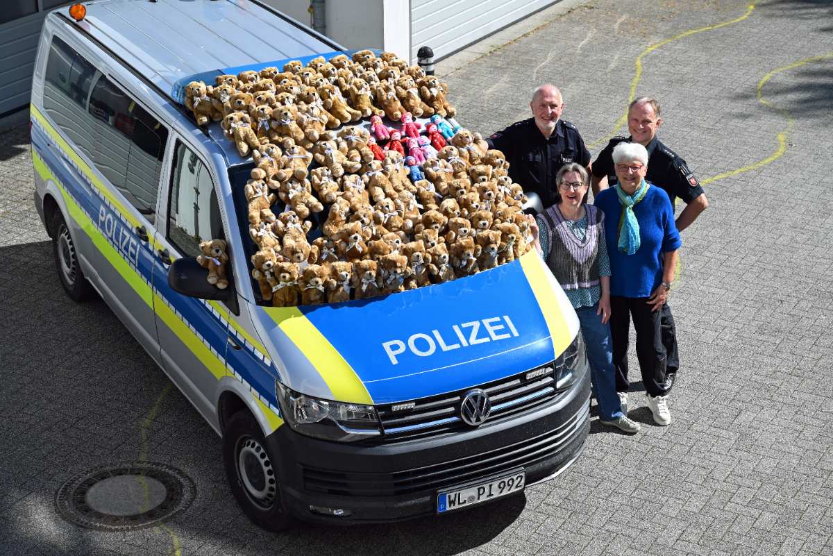 75 Trostteddys für die Polizei Harburg: Hilfe für Kinder in Not 1 a group of people standing next to a police van with teddy bears on the roof
