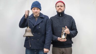 two men holding an hourglass and a bell