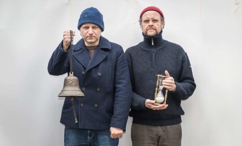 two men holding an hourglass and a bell