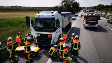 a group of people in orange jackets and white vests standing next to a truck