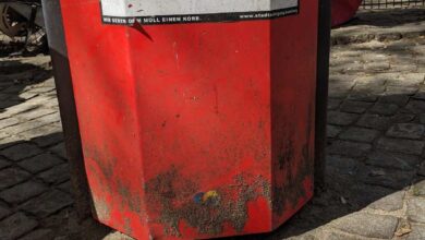a red trash can with a sign on it
