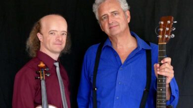 two men holding instruments and posing for the camera