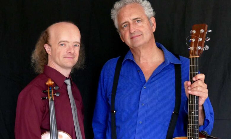 two men holding instruments and posing for the camera