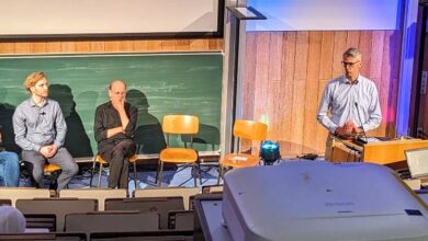 a group of people sitting in chairs in front of a green board