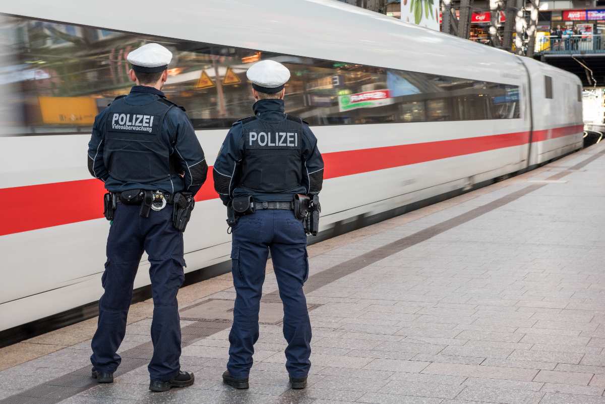 two police officers standing next to a train